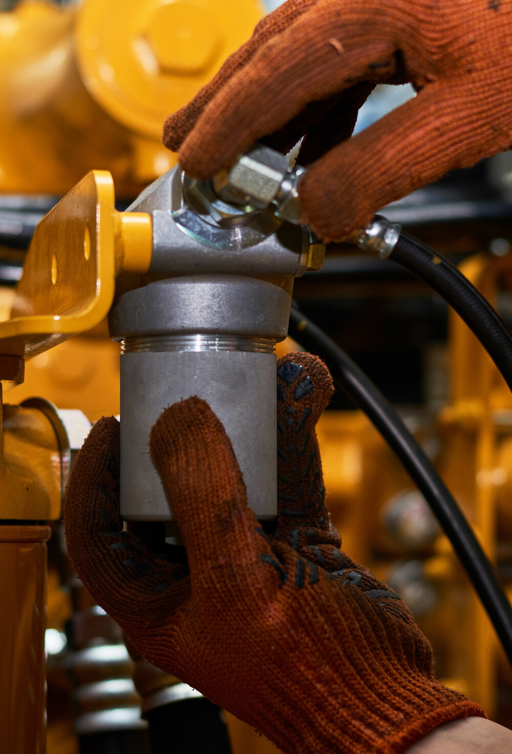 Industrimekaniker vedlikeholder hydraulikk på en industrimaskin.
