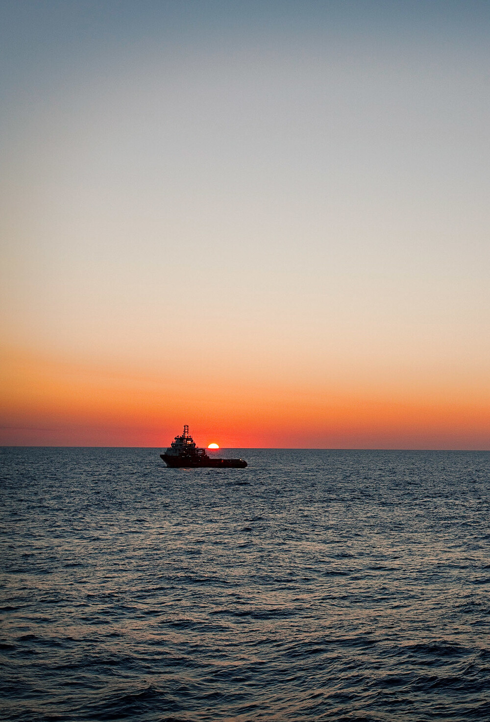Offshore-fartøy med solnedgang over horisonten.