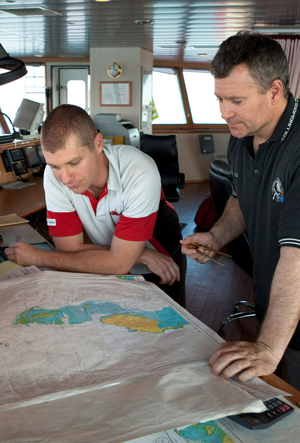 Styrmann og navigatør studerer et papirkart.